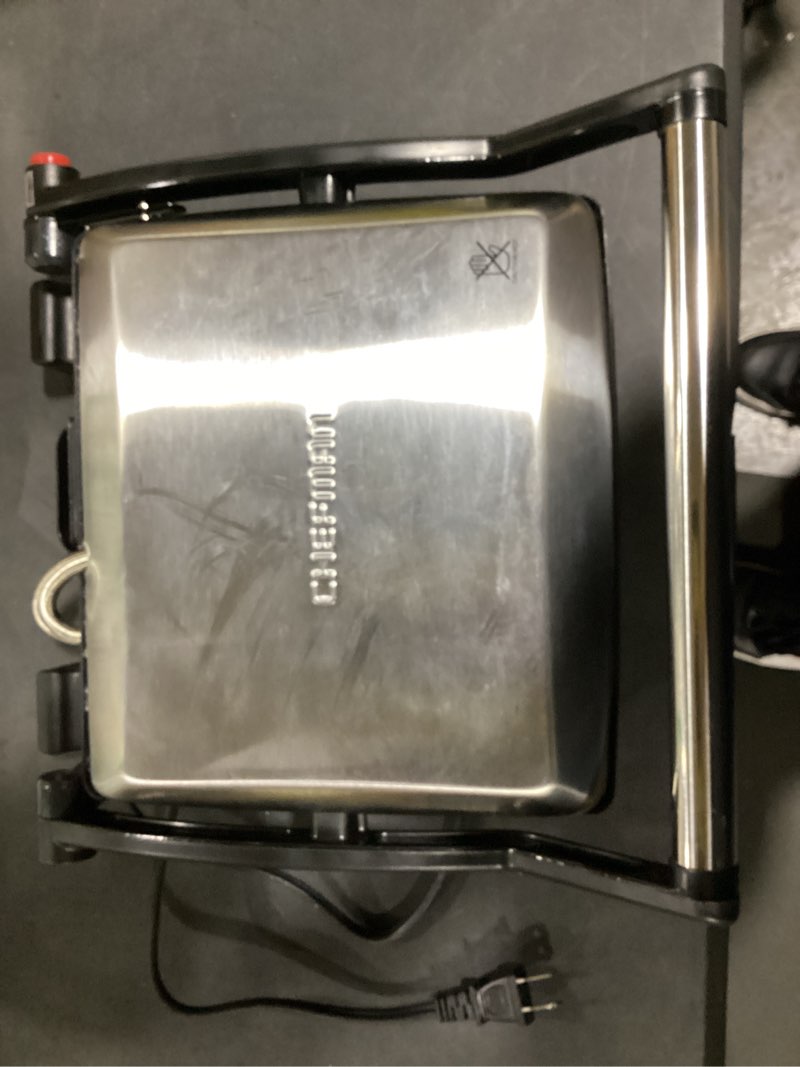 Condition photo showing Good Condition for Chefman Panini Press Grill and Gourmet Sandwich Maker Non-Stick Coated Plates, Opens 180 Degrees to Fit Any Type or Size of Food, Stainless Steel Surface and Removable Drip Tray, 4 Slice, Black 4 Slice - Standard (Small dent on top of lid)