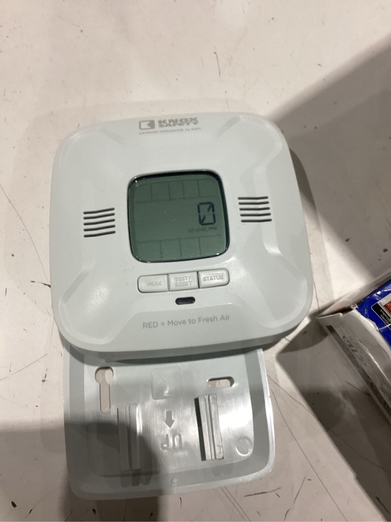 Condition photo showing As Is for battery operated carbon monoxide alarm, digital display, voice alerts, bilingual, ten year battery