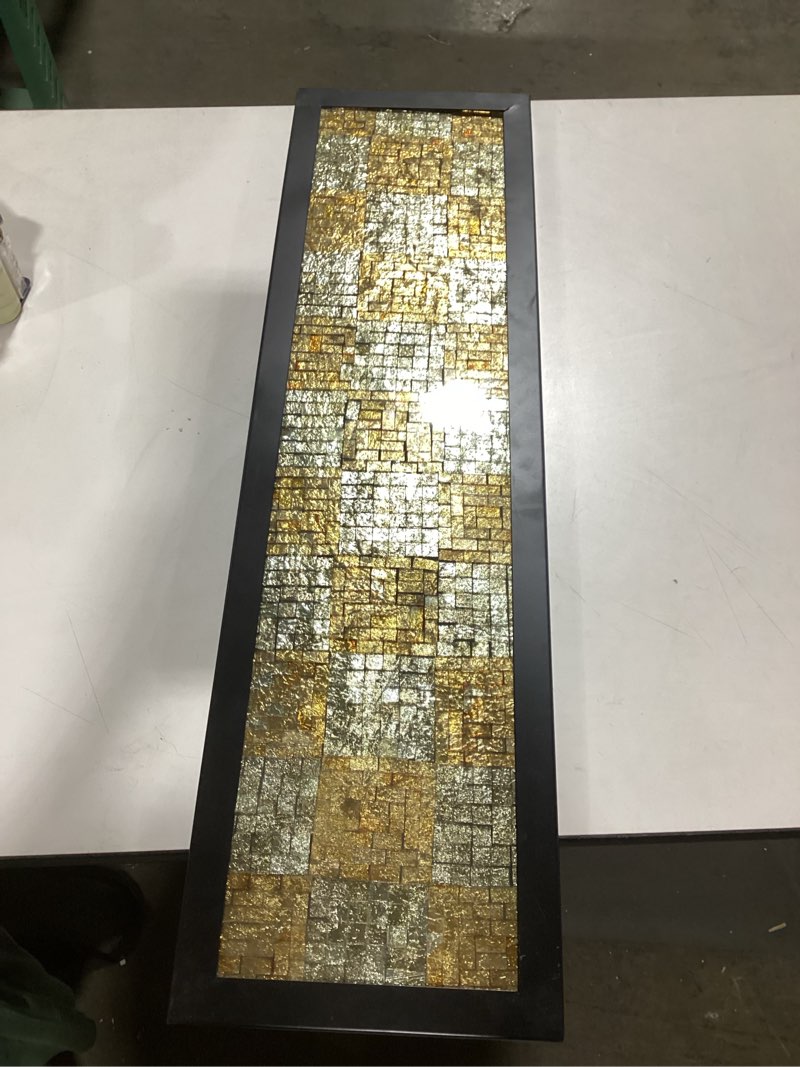 mosaic-like pattern of metallic tiles or leaf, with a mix of gold and silver tones, set within a dark frame.