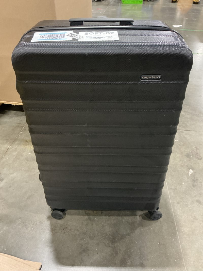 Condition photo showing As Is for amazon basics 30" hardside large checked luggage, hardshell suitcase with four multi-directional wheels, expandable for up to 15% more space, scratch-resistant shell, black black large checked