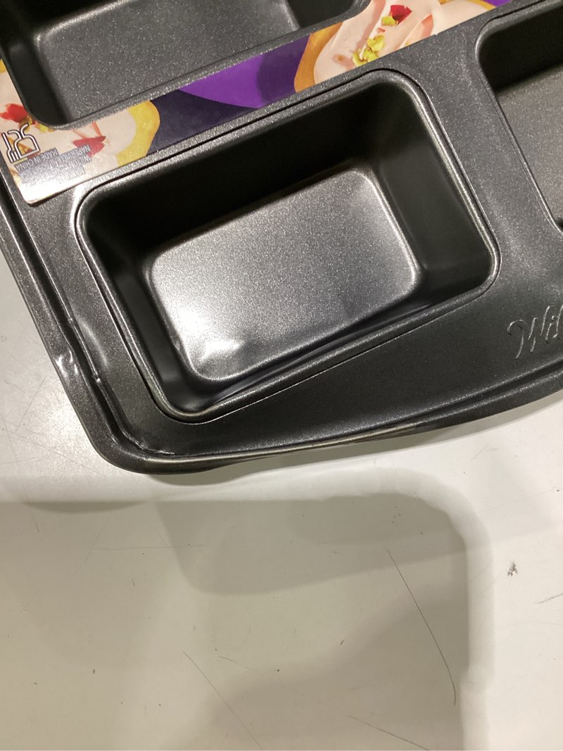 Condition photo showing As Is for wilton gold non-stick bakeware mini loaf - baking pan for mini banana breads, cakes & more - made without pfas - offers even heat distribution & hassle-free cleaning - 15 x 10 x 1.6 inch, 8 cavity mini loaf 15.2 in x 9.5 in x 1.6, slight dent