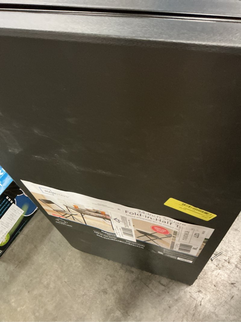 Condition photo showing As Is for mainstays 34" square resin fold-in-half table, rich black