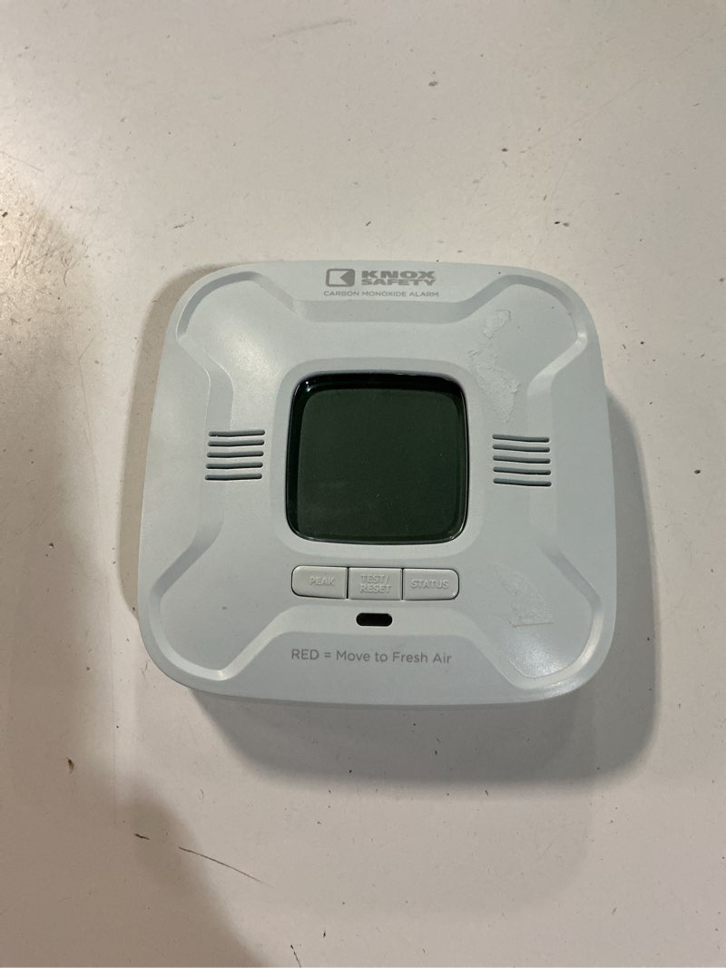 Condition photo showing As Is for battery operated carbon monoxide alarm, digital display, voice alerts, bilingual, ten year battery