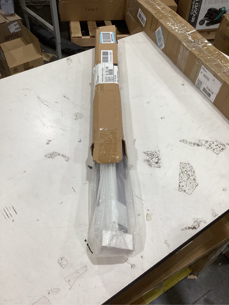 The image displays a packaged, long metal component, likely for a commercial door or furniture assembly, sitting on a shipping table.