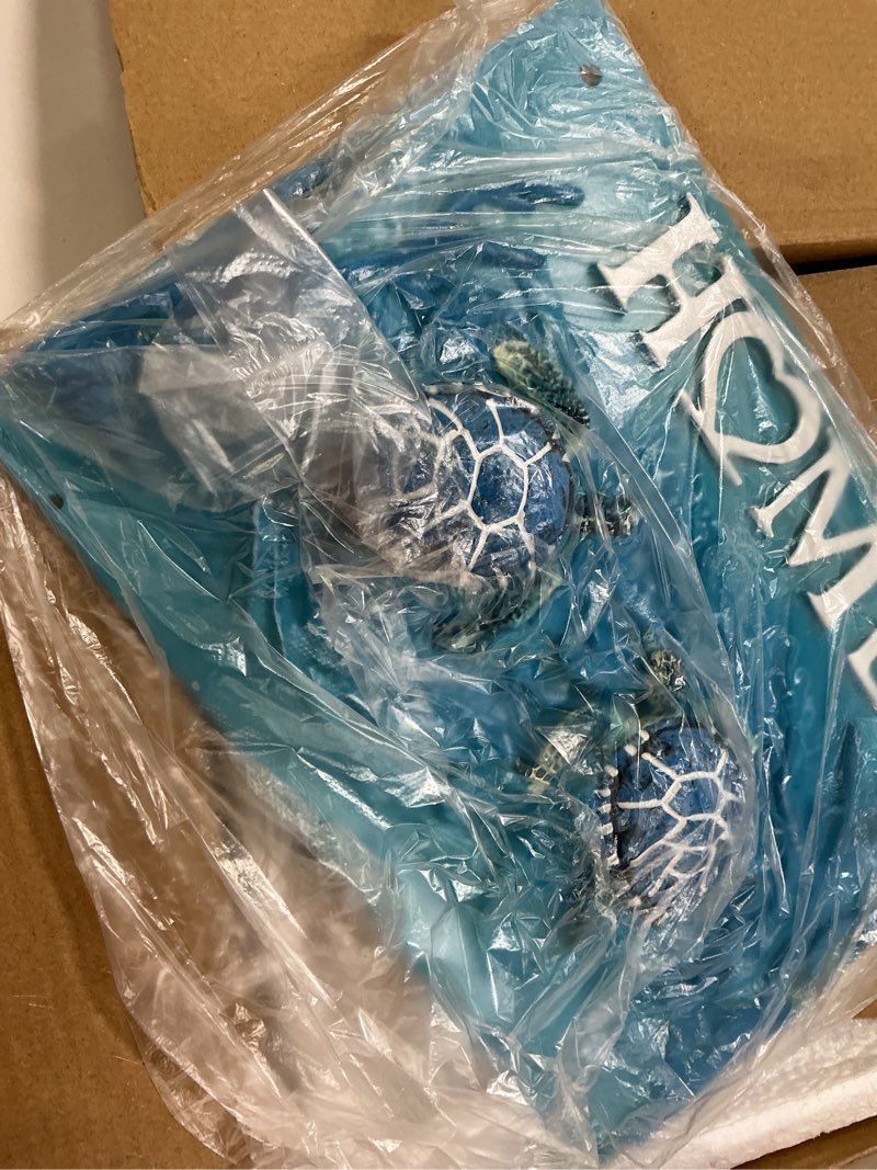Condition photo showing New/Like New for coastal-themed "home" wall plaque adorned with two detailed 3d blue sea turtles swimming amidst textured ocean waves and coral