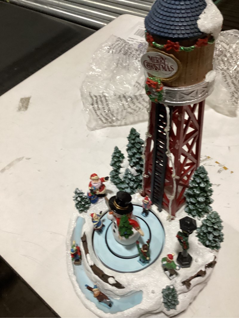 Condition photo showing As Is for MOMENTS IN TIME Christmas Village 14”H Polyresin LED Lighted Water Tower with Animated Scene (Adapter Included)