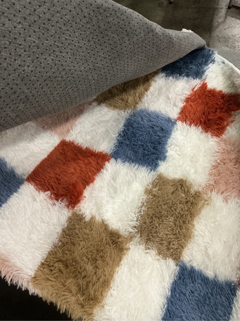 Condition photo showing Good Condition for decorative area rug featuring a plush, shaggy texture and a patchwork color block pattern. (unknown size)