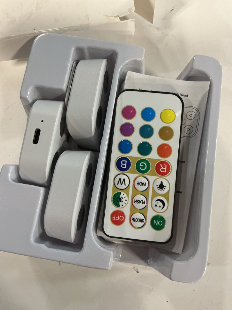 Condition photo showing As Is for Wireless Step Light Rechargeable Puck Lights with Charging Station, RGB Motion Sensor Puck Light Under Cabinet Lighting with Remote Control, LED Closet Lights for Stair, Kitchen (3 Pcs) Colorful Light 3 Pack with Stand