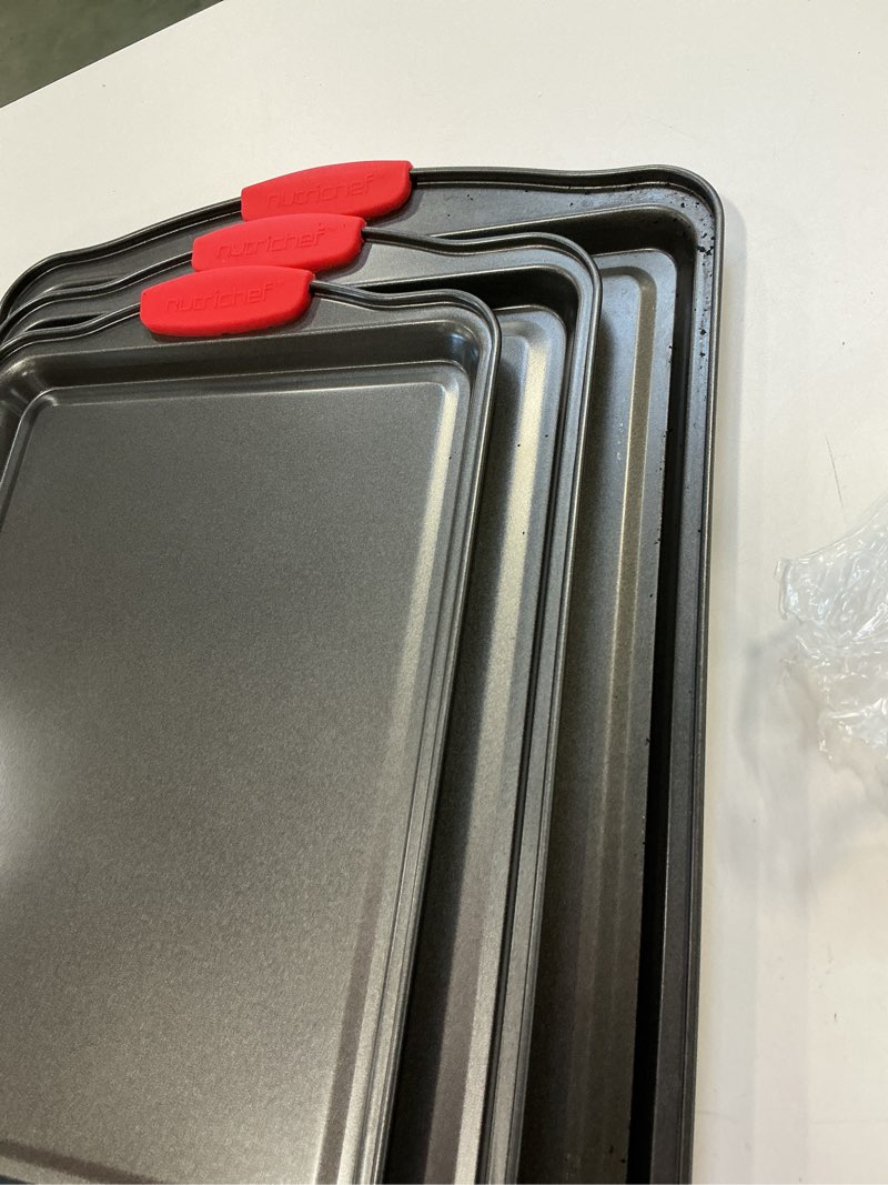 Condition photo showing As Is for NutriChef 3-Piece Nonstick Kitchen Oven Baking Pans - Premium & Stylish Non-Stick Steel, Commercial Grade Restaurant Quality Metal Bakeware with Red Silicone Handles - Easy to Clean, NCSBS3S 3-Piece Set