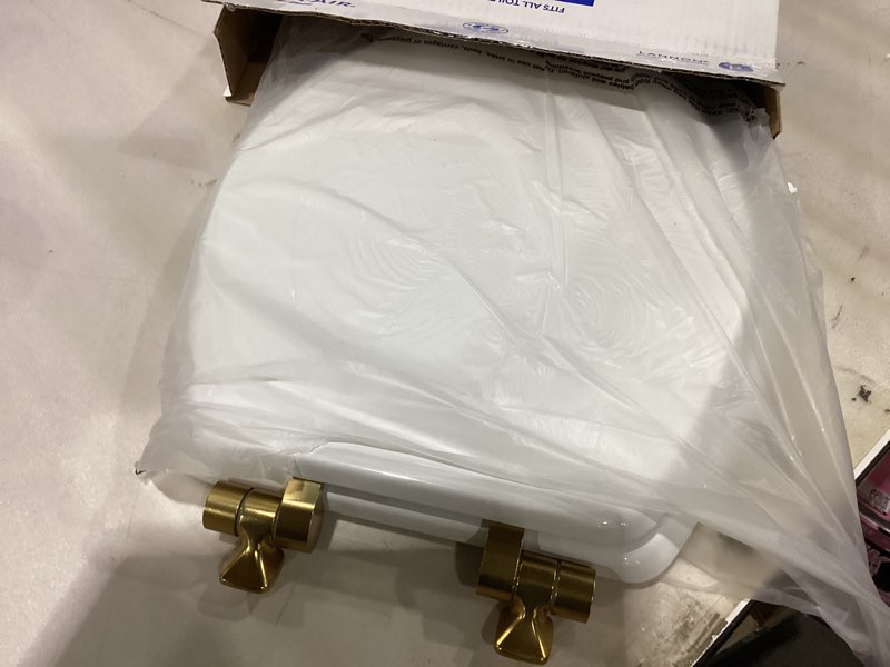 Condition photo showing As Is for Mayfair Bennett Toilet Seat with Brushed Gold Hinges, Slow Close Wood Seat, Secure Metal Hinges, Easy Install, Made in USA, Round, White Round Gold