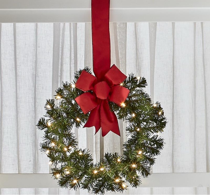 Hammacher 98679 Only available from Hammacher Schlemmer, this is the 18" cordless prelit outdoor window wreath that can adorn every window of your home without requiring proximity to an outlet. Each wreath is festooned with 35 glistening warm white LEDs and is weatherproof to withstand outdoor elements or shine beautifully indoors. A wide red bow decorates the greenery and serves as the wreath’s hanger. A built-in timer can be set to six hours on/18 hours off, or the lights can be operated manually with a switch on the wreath’s battery box or by using the included remote control. Requires three AA batteries. Includes one wreath. 18" H x 18" W x 3" D. (1 lb.)