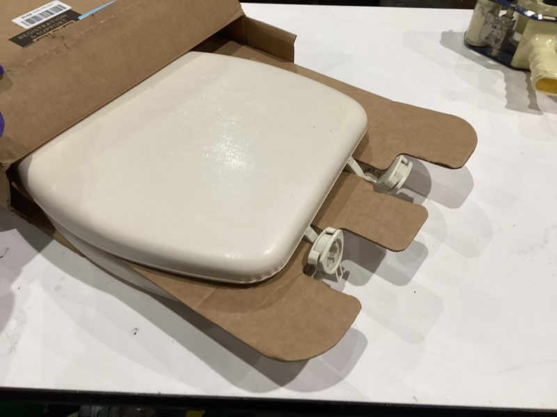 Condition photo showing As Is for Mayfair Padded Toilet Seat, Cushioned Soft Vinyl over Wood Core Seat, Secure Hinges, Easy Clean, Elongated, Bone Elongated Bone Toilet Seat
