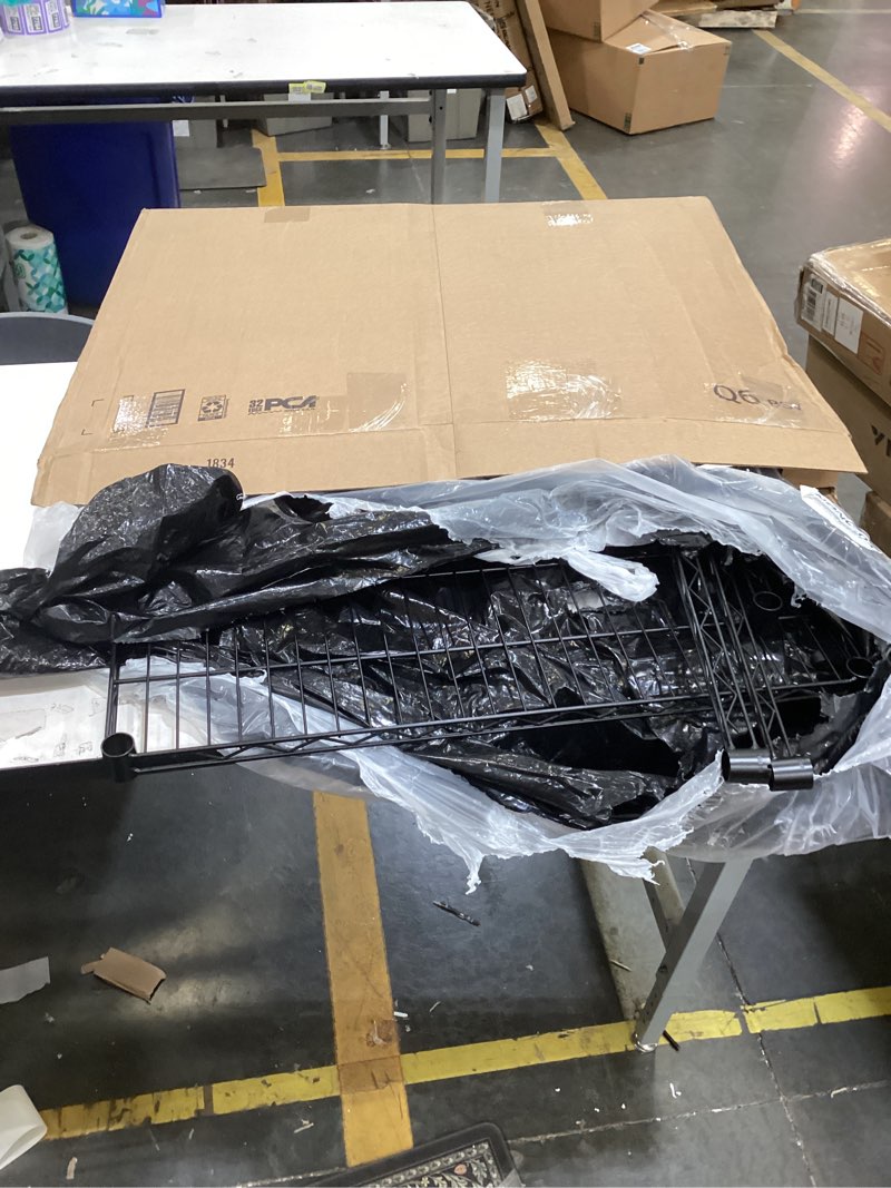 The image displays a black metal wire shelving unit, similar in style to industrial or home storage racks. These units are typically constructed from heavy-duty steel and are adjustable for various storage needs.  