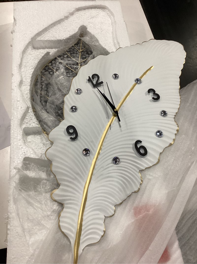 Condition photo showing New/Like New for 18x27 inch large modern feather leaf shape wall clock for living room decor, white unique silent decorative art clock for home bedroom office dining kitchen