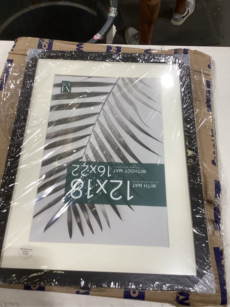 Condition photo showing Good Condition for mcs studio gallery 16x22 matted poster frame with 12x18 picture display, black woodgrain engineered wood vertical & horizontal wall hanging large picture frame for photos, posters & art prints (1-pack) 1-pack black woodgrain 12x18