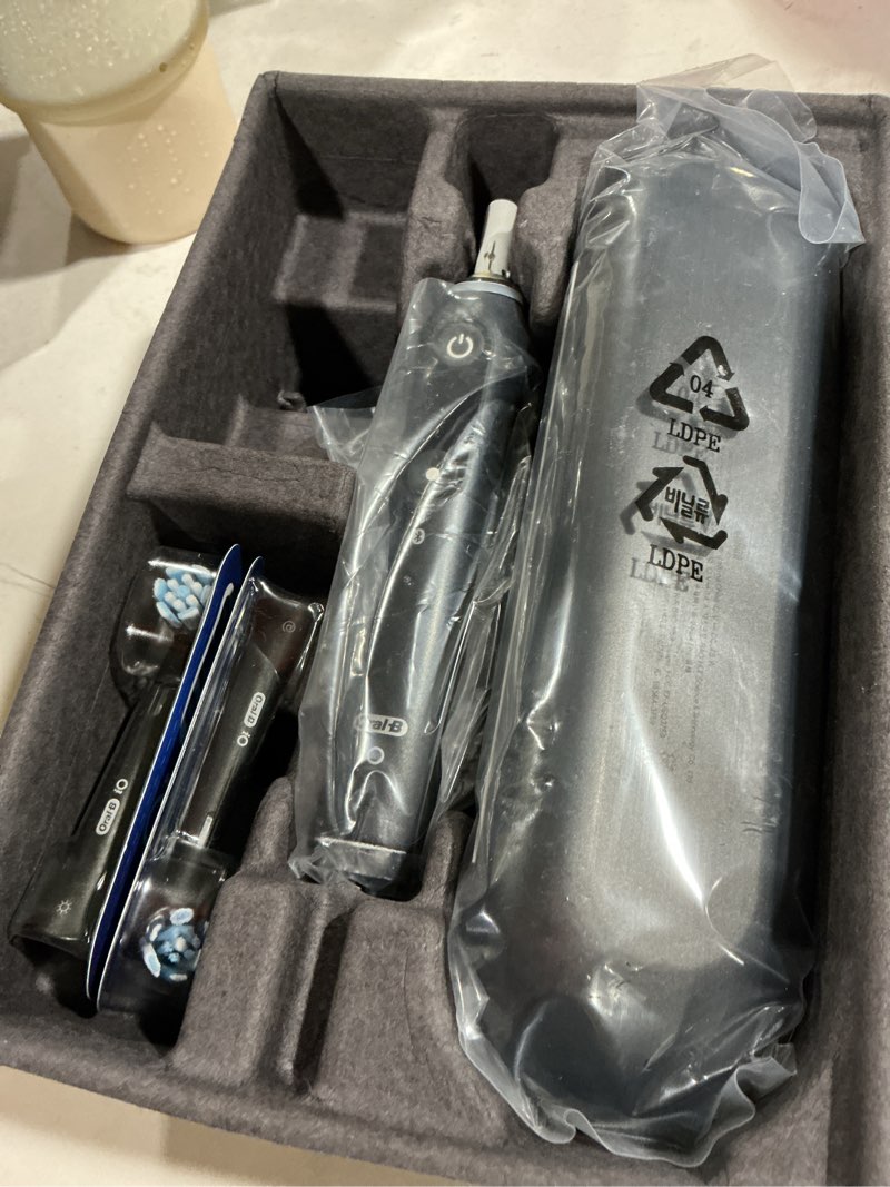 Condition photo showing As Is for oral-b rechargeable electric toothbrush, io9 limited ultimate clean, 7 cleaning modes, interactive display, isense charger, charging travel case, visible pressure sensor, 3 brush heads, black