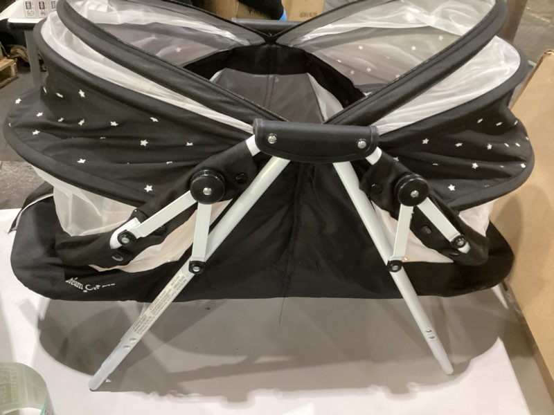 Condition photo showing As Is for dream on me karley bassinet in black, lightweight portable baby bassinet, quick fold and easy to carry, adjustable double canopy, indoor and outdoor bassinet with large storage basket., similar to stock photo