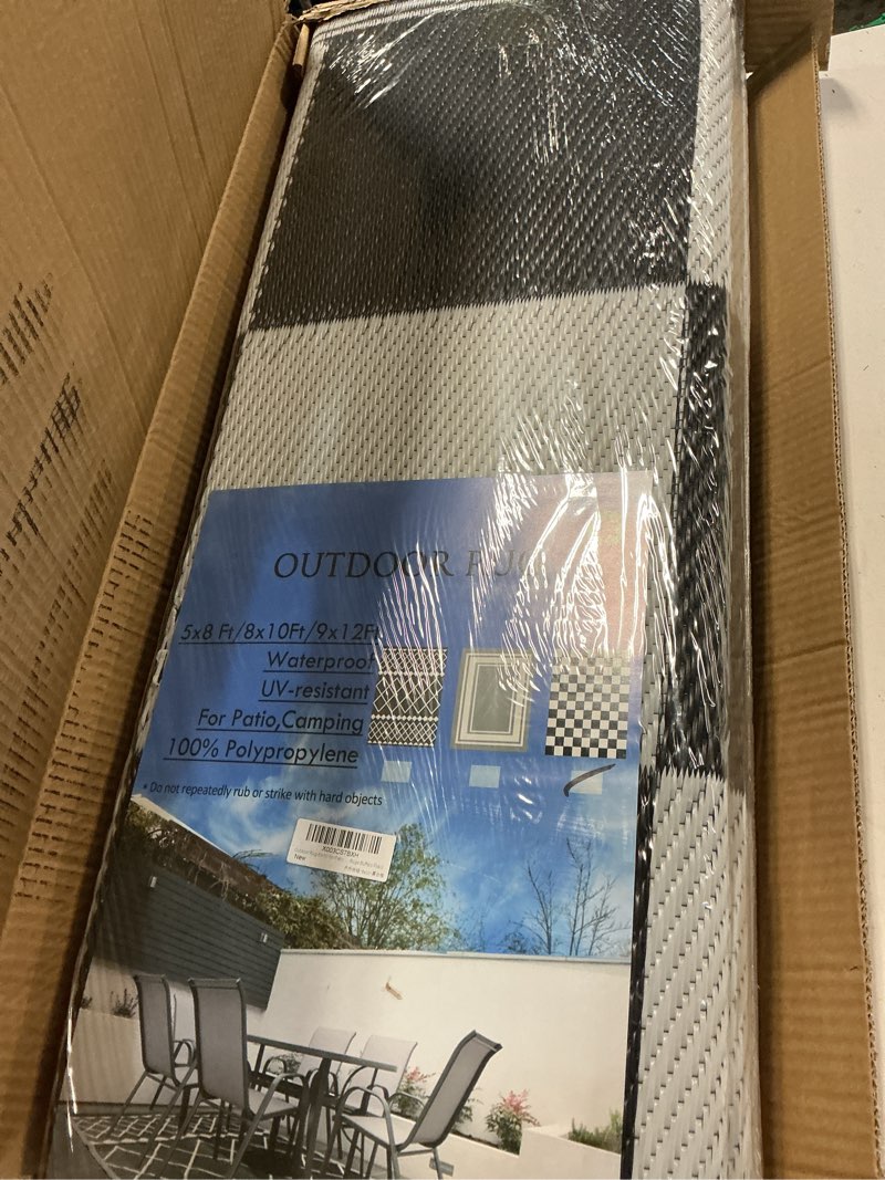 Condition photo showing New/Like New for outdoor 8'x10' geometric waterproof reversible plastic straw rug, black & white check